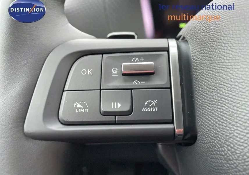 Gros plan sur les commandes au volant du Citroën C4 2024 gris platinium, avec boutons de régulateur et assistant de conduite.