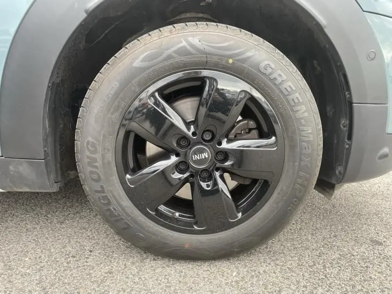 Gros plan sur la roue avant gauche d'une MINI Countryman Cooper 136 gris 2021 avec jante noire brillante.