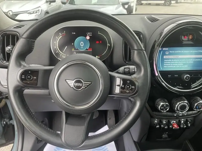 Vue intérieure centrée sur le volant et le tableau de bord numérique d'une MINI Countryman gris 2021 avec écran tactile circulaire.