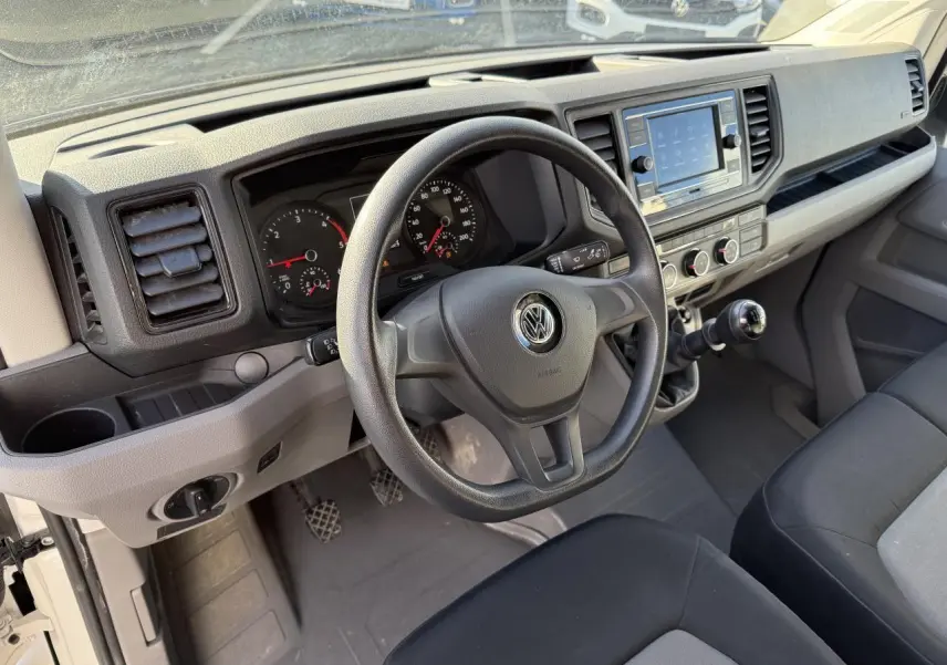 Vue intérieure du tableau de bord et volant multifonctions noir du Volkswagen Crafter Fourgon blanc 2023 avec boîte manuelle.