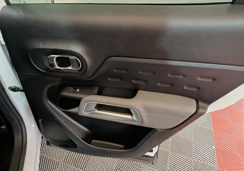 Vue intérieure côté gauche de la porte avant d’un Citroën C5 Aircross Hybrid blanc avec poignée argentée et accoudoir gris.