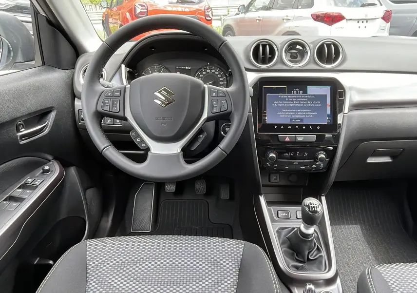 Vue intérieure centrée sur le volant multifonctions et la console centrale avec écran tactile de la Suzuki Vitara 2025.