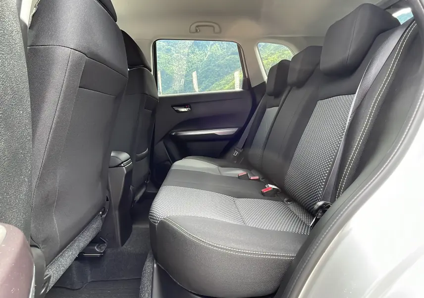 Vue latérale intérieure sur la banquette arrière noire et grise du Suzuki Vitara 2025, avec ceinture de sécurité et fenêtre ouverte.