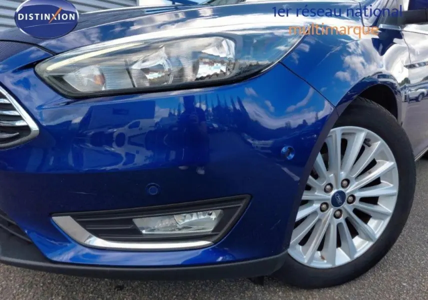 Gros plan sur l'avant droit bleu foncé d'une Ford Focus SW 2018 avec jante alliage 17 pouces et phare allumé.