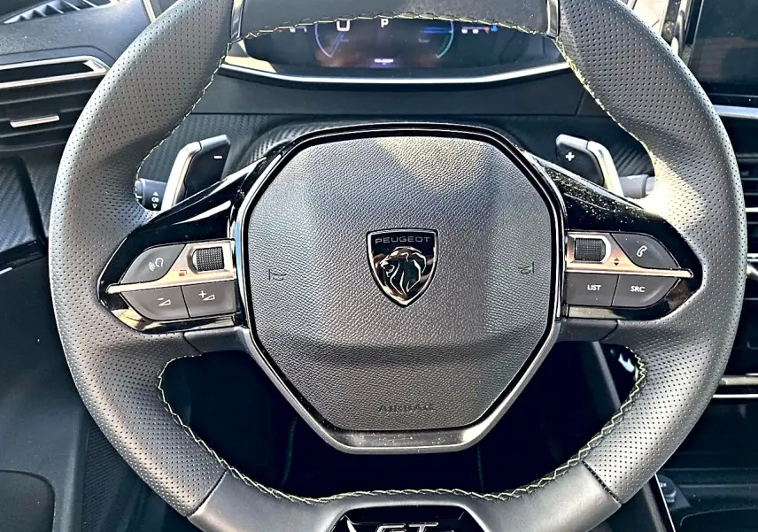 Vue rapprochée du volant cuir noir perforé du Peugeot 2008 1.2 hybrid 145 GT avec logo et commandes intégrées.
