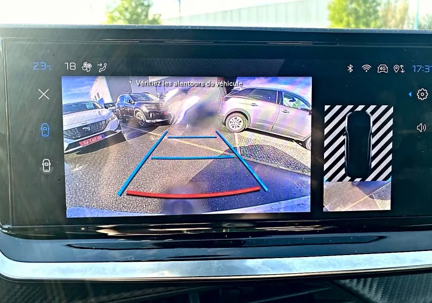 Écran tactile montrant la caméra de recul d’un Peugeot 2008 noir avec guidage de trajectoire en bleu et rouge.