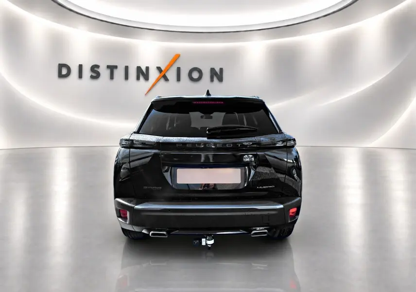 Vue arrière d’un Peugeot 2008 noir 2025 avec attelage, feux LED et becquet arrière dans un showroom lumineux.