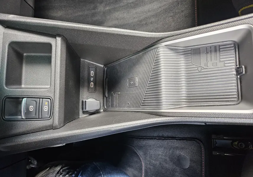 Vue plongeante sur la console centrale noire de la Renault R5 Iconic 2025, avec zone de recharge sans fil et ports USB.