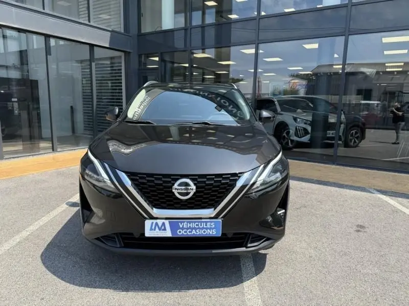 Vue frontale d'un Nissan Qashqai noir 2023, version 1.3 Mild Hybrid N-Connecta, stationné devant une vitrine.