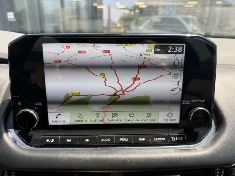 Écran tactile central du Nissan Qashqai 2023 affichant la navigation avec carte routière et commandes audio en dessous.