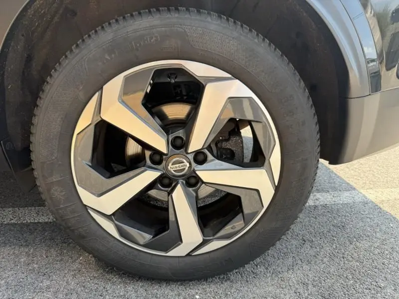 Gros plan sur la roue avant droite du Nissan Qashqai noir 2023, mettant en valeur la jante alliage au design géométrique.