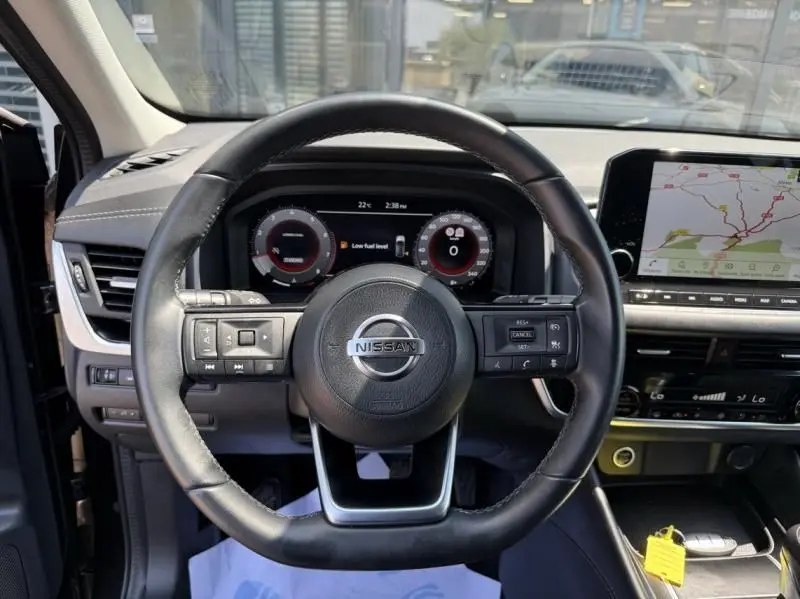 Vue intérieure centrée sur le volant du Nissan Qashqai noir 2023, avec tableau de bord digital et écran de navigation.