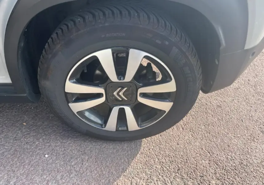 Gros plan sur la roue avant gauche avec jante alliage diamantée et logo Citroën sur un C3 Aircross beige.