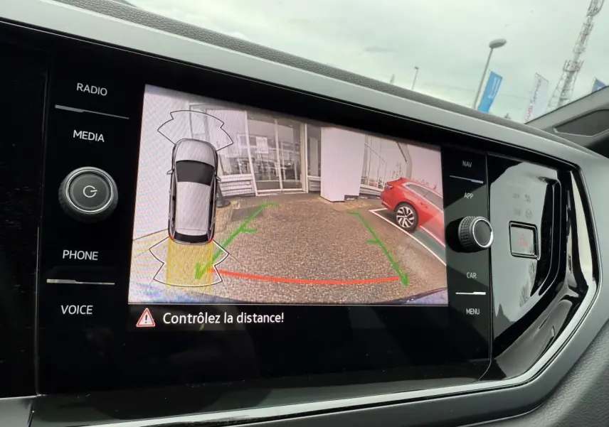 Écran tactile intérieur affichant la caméra de recul du Volkswagen Polo bleu récif métallisé avec aide au stationnement active.