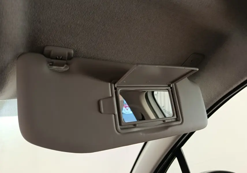 Miroir de courtoisie ouvert sur le pare-soleil côté conducteur d'une Citroën C3 blanche, vue intérieure rapprochée.