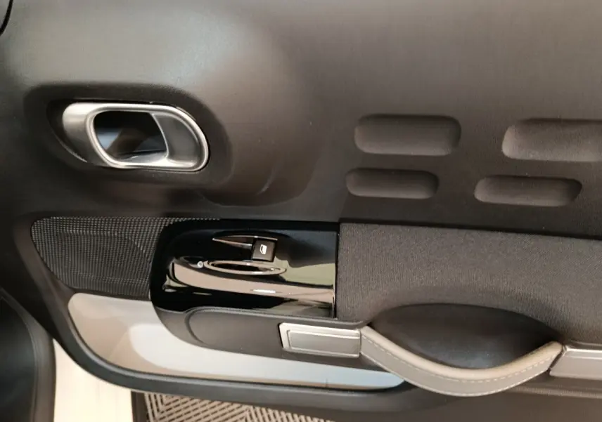 Détail de la porte intérieure côté conducteur de la Citroën C3 blanche, avec poignée argentée et commandes de vitre.