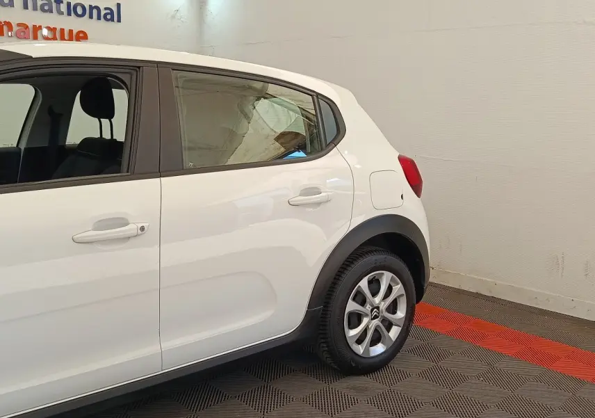 Vue latérale droite d'une Citroën C3 blanche, mettant en valeur les jantes alliage et les protections noires autour des passages de roue.