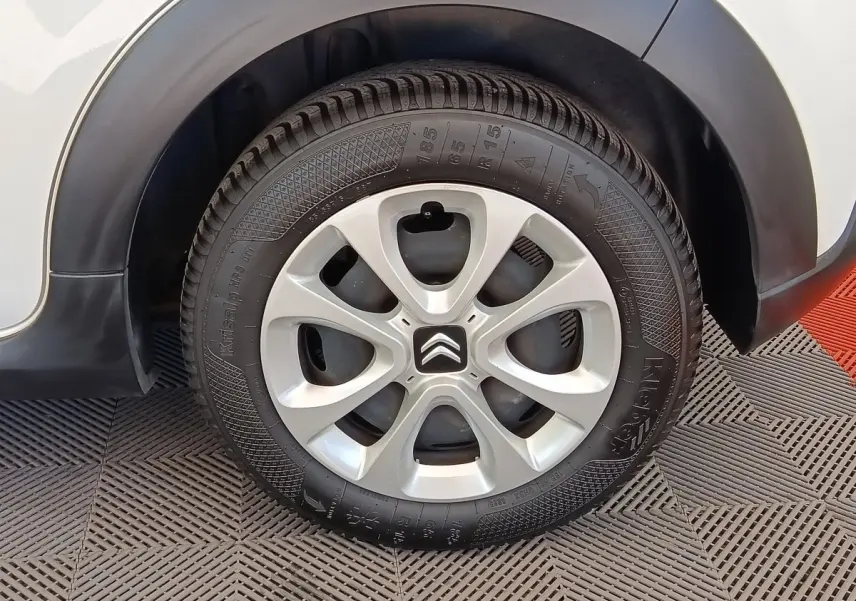 Gros plan sur la roue arrière droite d'une Citroën C3 blanche avec jante alliage et logo Citroën central.