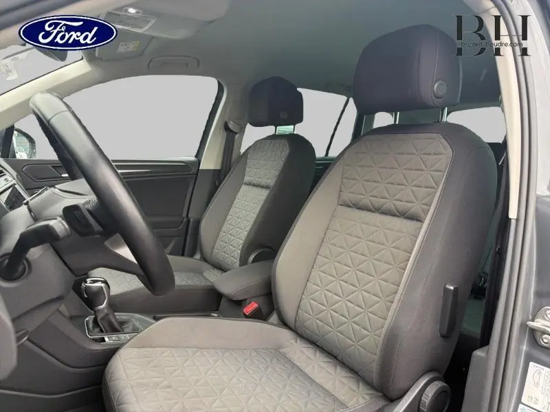 Vue intérieure côté conducteur du Volkswagen Tiguan 1.5 TSI gris avec sièges tissu anthracite à motifs géométriques.