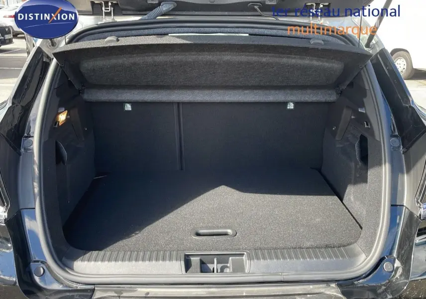 Coffre ouvert en vue arrière d’un Renault Captur 2025 noir étoile métal avec toit gris, intérieur de coffre spacieux et propre.