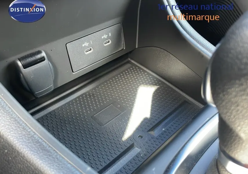 Gros plan sur la console centrale du Renault Captur 2025, montrant un espace de rangement avec ports USB et prise 12V.