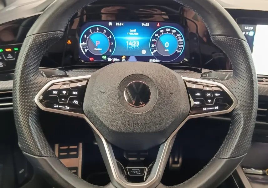 Gros plan sur le volant cuir multifonctions de la Volkswagen Golf 1.5 eTSI R-Line avec tableau de bord numérique lumineux.