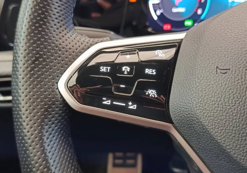 Gros plan sur les commandes du régulateur de vitesse au volant cuir noir de la Volkswagen Golf 1.5 eTSI R-Line 2021.
