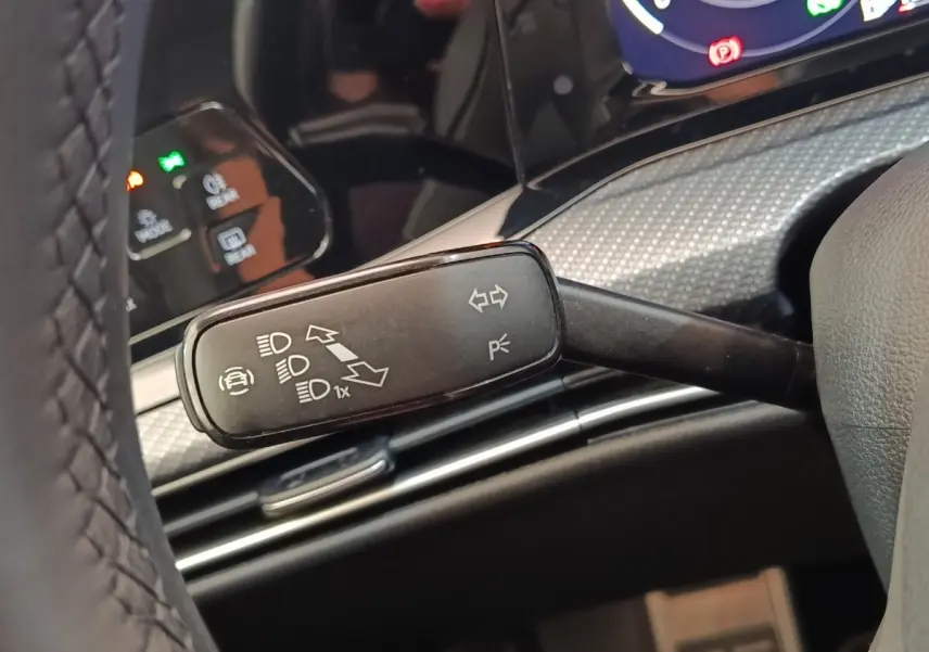 Gros plan sur la manette de clignotant et feux dans l’habitacle d’une Volkswagen Golf noire, tableau de bord en arrière-plan.