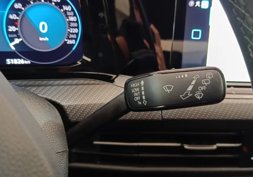 Gros plan sur la commande d’essuie-glace à gauche du volant dans l’habitacle noir d’une Volkswagen Golf 1.5 eTSI 2021.