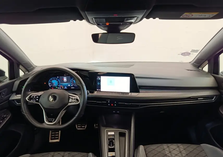 Vue intérieure avant de la Volkswagen Golf 1.5 eTSI R-Line 2021, tableau de bord noir avec écran tactile et volant cuir multifonctions.