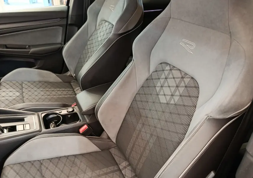 Vue rapprochée des sièges avant gris et noirs de la Volkswagen Golf 1.5 eTSI R-Line avec surpiqûres et logo R-Line brodé.