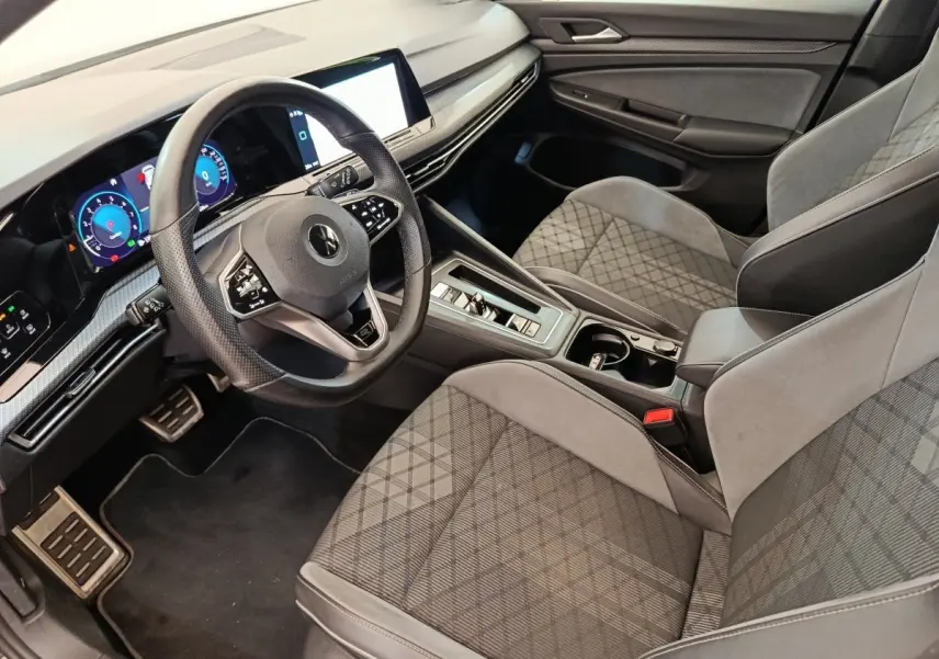 Vue intérieure côté conducteur de la Volkswagen Golf 1.5 eTSI R-Line 2021, sièges gris à motif géométrique et tableau de bord digital.