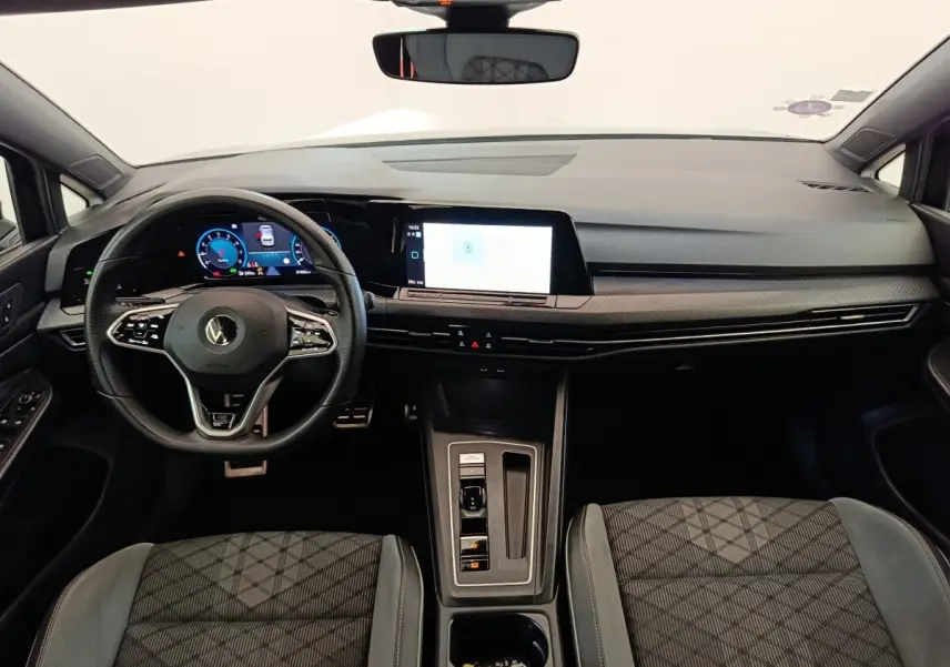 Vue intérieure avant de la Volkswagen Golf 1.5 eTSI R-Line 2021, tableau de bord moderne avec écran tactile et volant cuir.