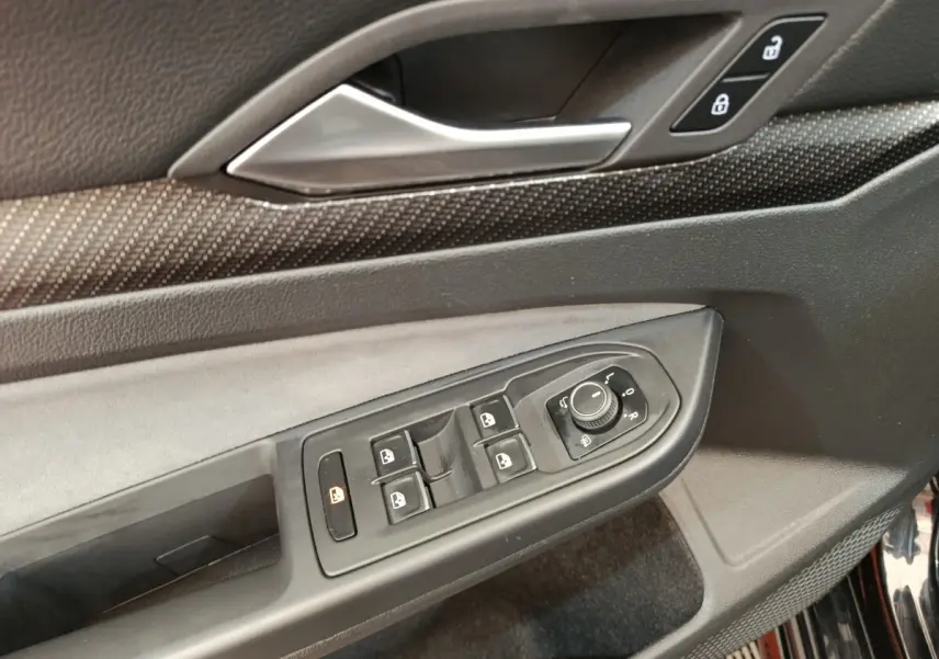Détail de la commande des vitres et rétroviseurs côté conducteur de la Volkswagen Golf 1.5 eTSI noire, intérieur noir.