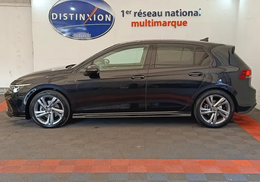 Volkswagen Golf 1.5 eTSI R-Line noire vue de profil côté gauche dans un showroom avec jantes alliage.