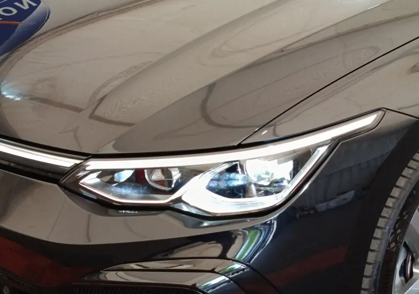 Gros plan sur le phare avant droit d'une Volkswagen Golf 1.5 eTSI noire, mettant en valeur le design LED moderne.