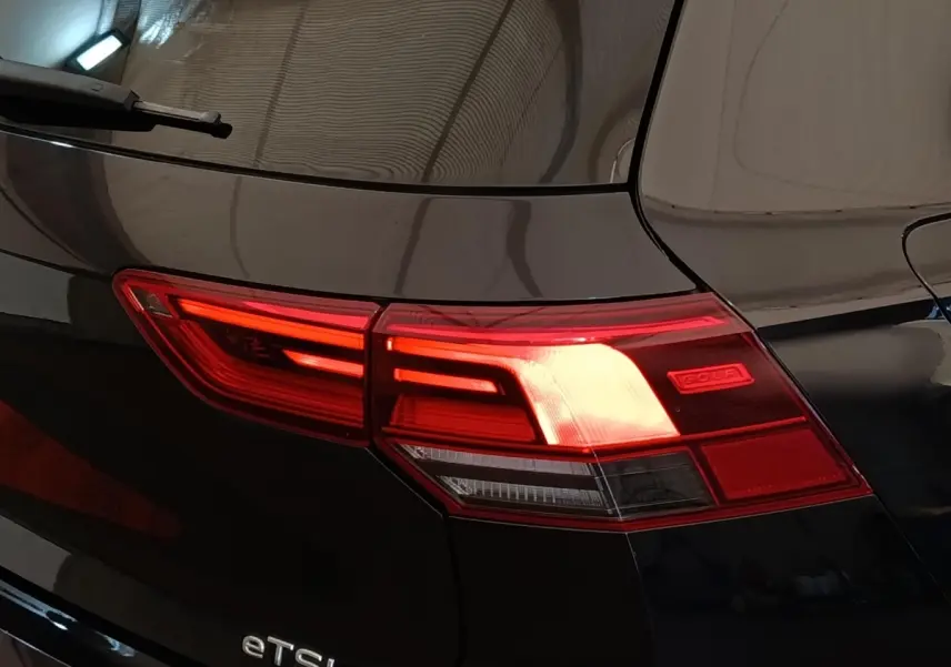Feu arrière droit allumé d'une Volkswagen Golf noire 1.5 eTSI R-Line, vue rapprochée sur le coffre.