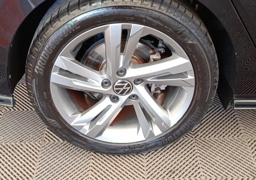Gros plan sur la roue avant droite de la Volkswagen Golf noire, jante alliage R-Line avec logo VW au centre.