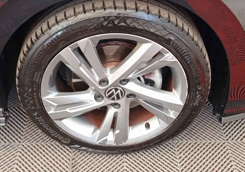 Gros plan sur la roue avant droite d'une Volkswagen Golf noire, avec jante alliage argentée à cinq branches.