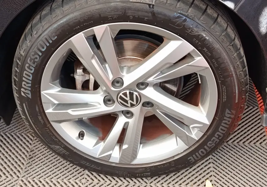 Gros plan sur la jante alliage argentée avec logo Volkswagen au centre d'une Golf noire 1.5 eTSI R-Line.
