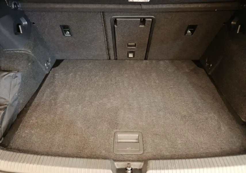 Vue intérieure du coffre de la Volkswagen Golf 1.5 eTSI noir, montrant la banquette arrière rabattable et la trappe à ski.
