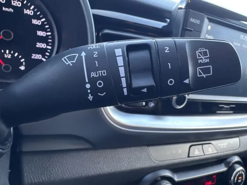 Gros plan sur la commande des essuie-glaces du Kia Stonic brun sienna, avec tableau de bord et écran tactile en arrière-plan.