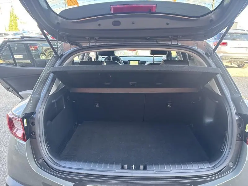 Vue arrière du coffre ouvert d'un KIA Stonic brun Sienne, montrant l'espace de chargement et la tablette cache-bagages.