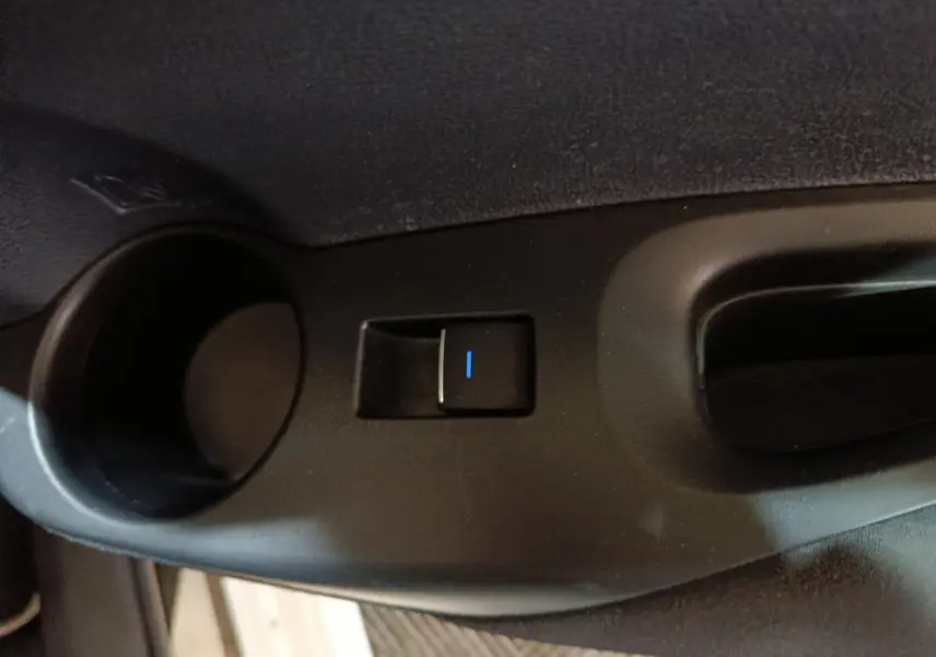 Bouton de commande électrique de la fenêtre sur la porte intérieure côté conducteur d'une Toyota Corolla blanche hybride.