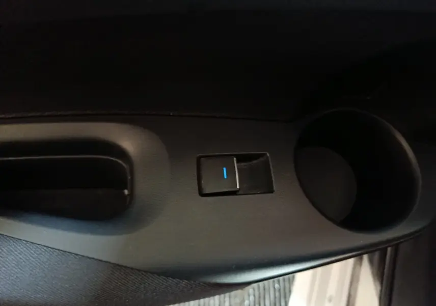 Gros plan sur la commande de lève-vitre et porte-gobelet côté conducteur d'une Toyota Corolla blanche hybride 2022.