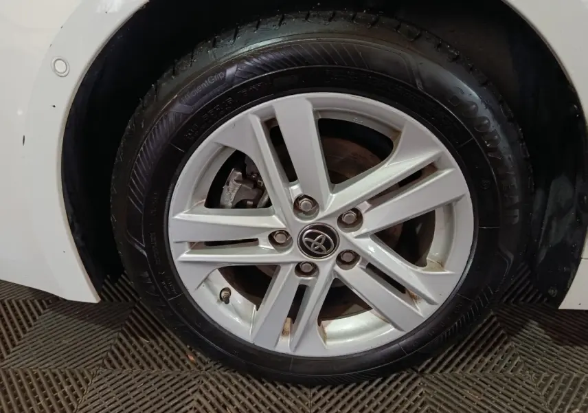 Gros plan sur la roue avant gauche blanche d'une Toyota Corolla hybride avec jante alliage et logo Toyota central.