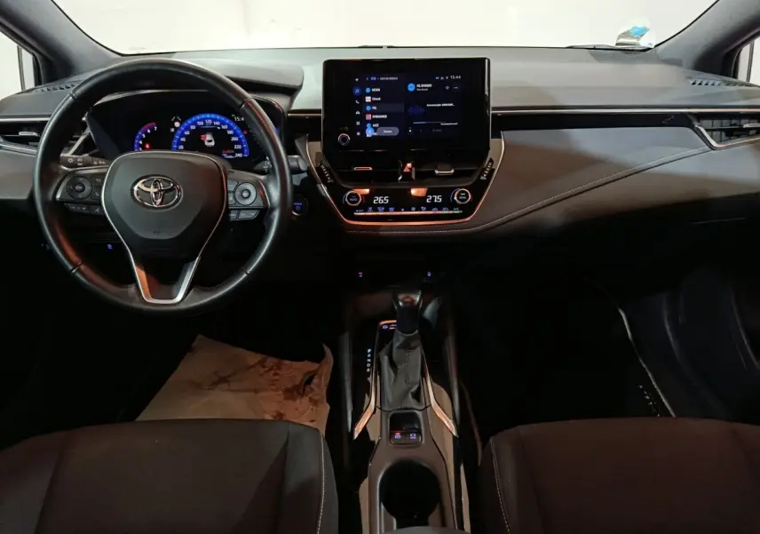 Vue intérieure frontale du tableau de bord et volant cuir noir de la Toyota Corolla Hybride 2022 avec écran tactile central.