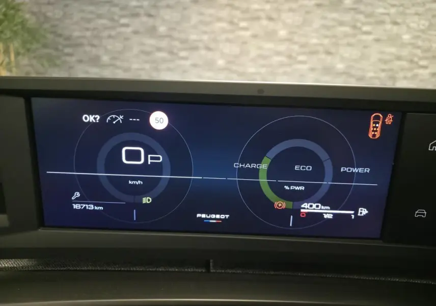 Affichage numérique du tableau de bord Peugeot 5008 hybride, indiquant vitesse, autonomie et modes charge, éco et puissance.