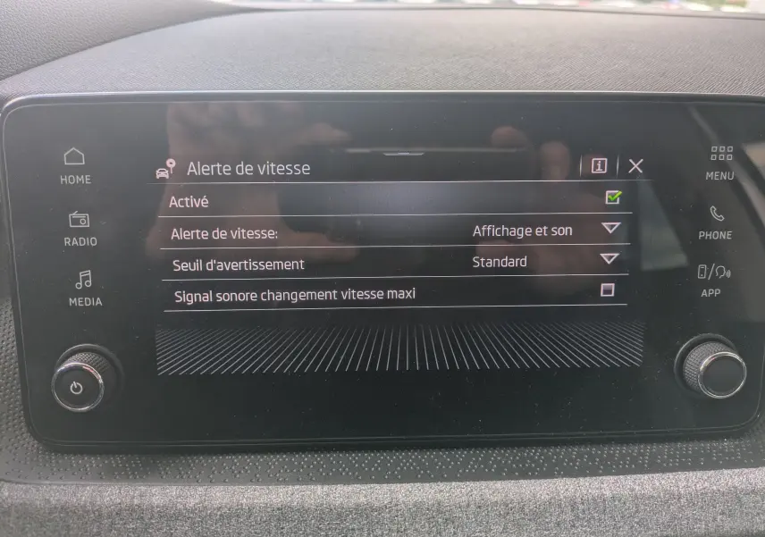 Écran tactile central du Skoda Scala gris Reflex 2025 affichant le menu des alertes de vitesse avec options activées.