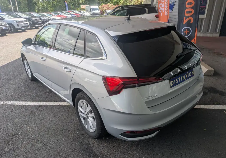 Vue 3/4 arrière droite d'une Skoda Scala gris reflex avec vitres teintées et feux arrière LED, stationnée en extérieur.